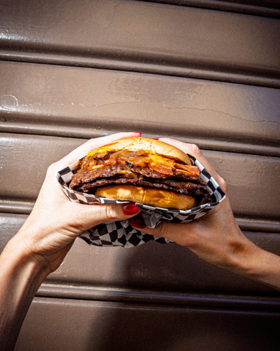 Smash burger tenuto in mano nel cestino a scacchi