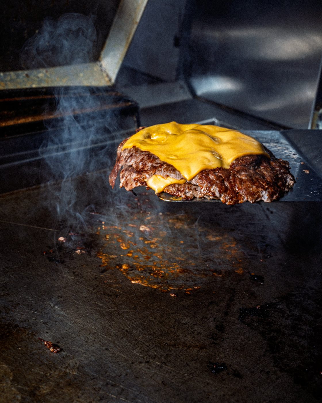 Patty di smash burger con cheddar fuso sulla spatola
